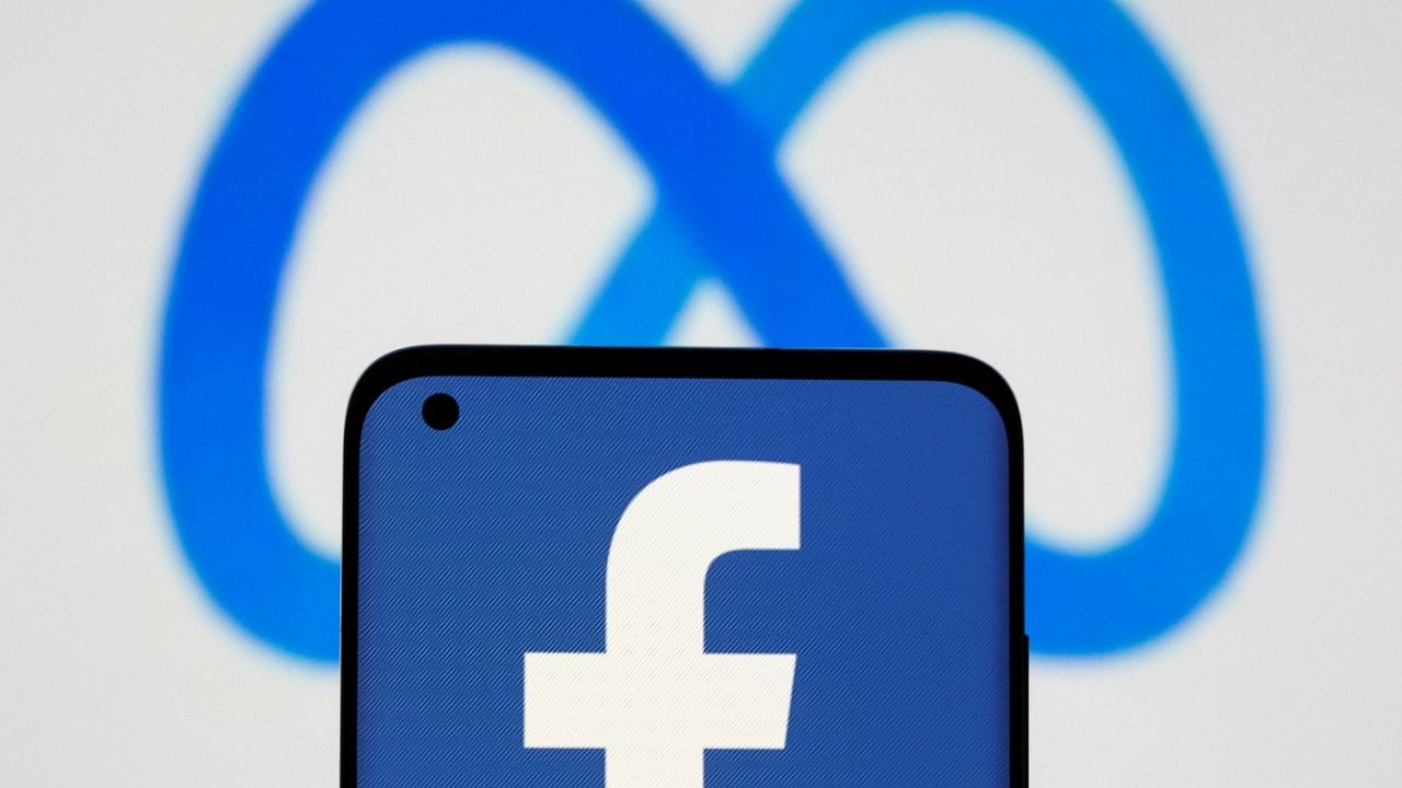 Facebook's new rebrand logo Meta is displayed behind a smartphone with Facebook logo in this illustration picture. Credit: Reuters File Photo