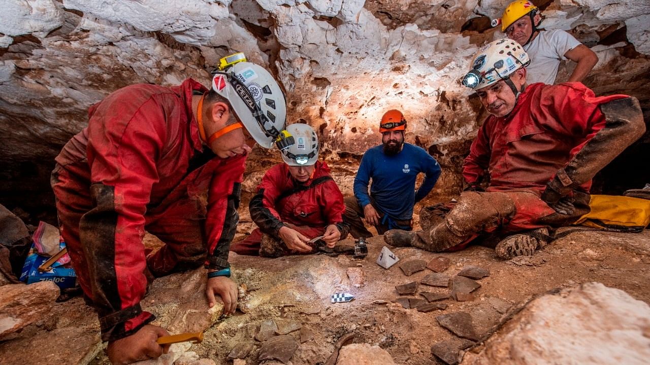 Archeologists of the National Institute of Anthropology and History (INAH) observe fragments of pottery in a cave, as part of the archeological work accompanying the construction of a controversial new tourist train, in the state of Yucatan, in this handout released on October 29, 2021. Mexico's National Institute of Anthropology and History Credit: (INAH)/Handout via Reuters