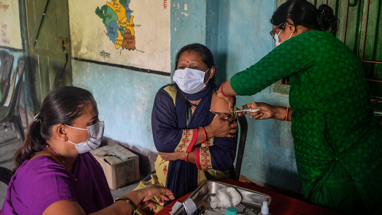 A health worker inoculates a woman with a dose of the Covishield vaccine against the Covid-19 coronavirus at a vaccination camp in Milanmore village. Credit: AFP Photo