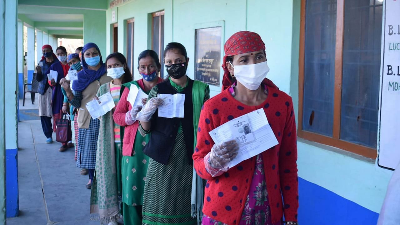 Voters show their identity cards before casting their respective votes at a polling station, for the Lok Sabha by-polls of Mandi constituency, Saturday. Credit: PTI Photo