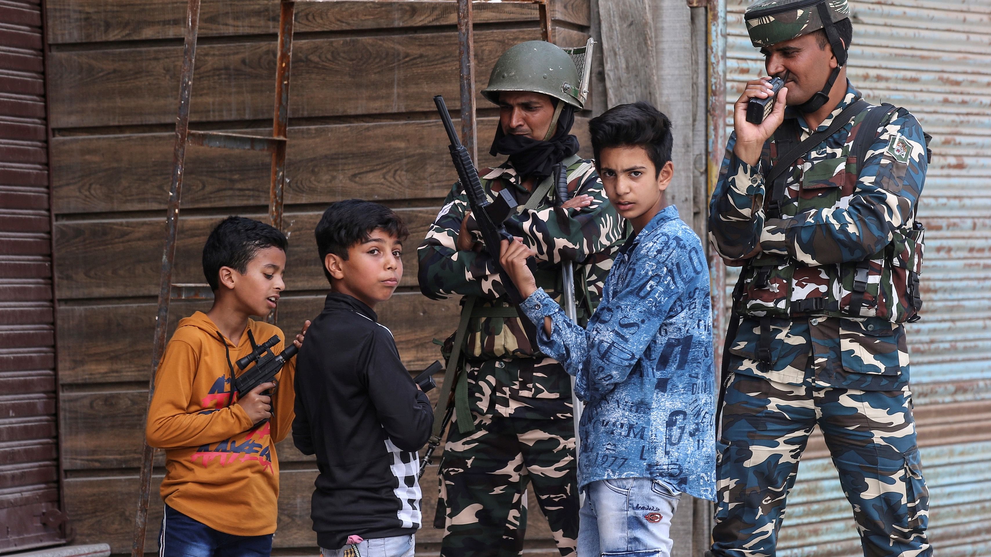 Children play with toy guns next to Indian security force personnel during restrictions after the scrapping of the special constitutional status for Kashmir by the government, in Srinagar. Credit: Reuters File Photo