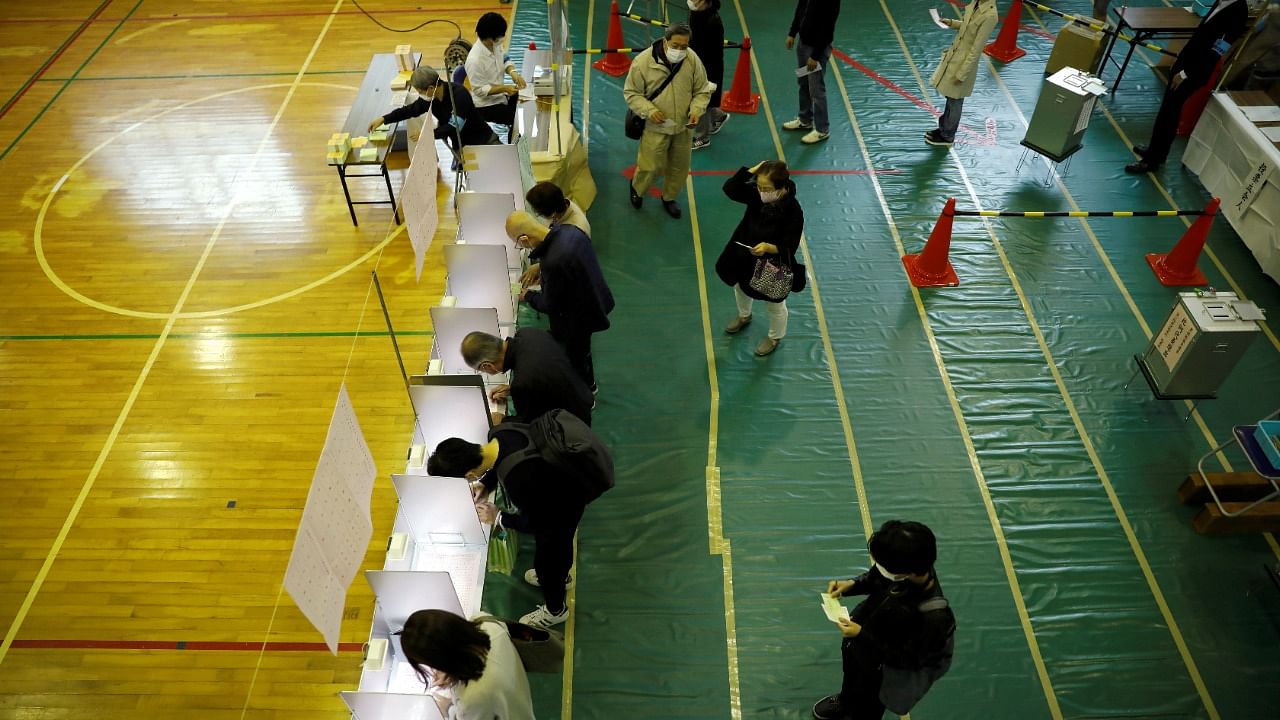 A voter casts a ballot in the lower house election at a polling station as other voters prepare their ballots in Tokyo, Japan. Credit: Reuters Photo