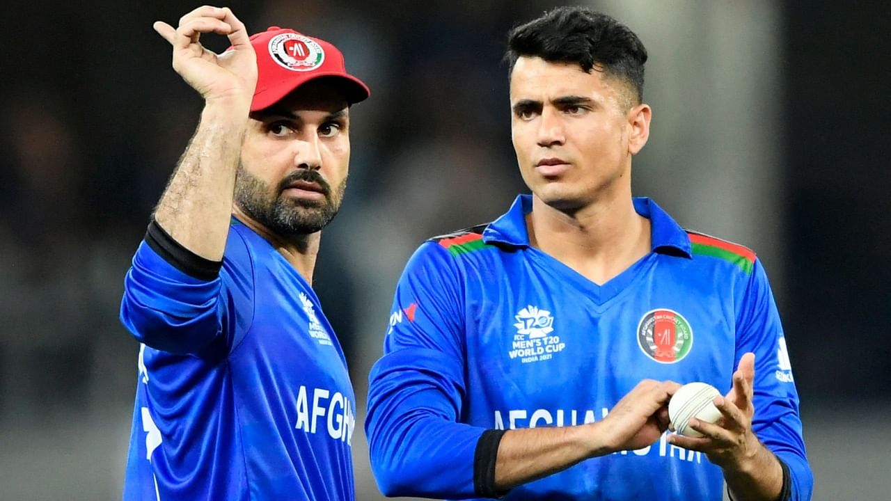Afghanistan's captain Mohammad Nabi (L) gestures next to his teammate Mujeeb Ur Rahman during the ICC men’s Twenty20 World Cup cricket match between Afghanistan and Pakistan at the Dubai International Cricket Stadium in Dubai on October 29, 2021. Credit: AFP Photo
