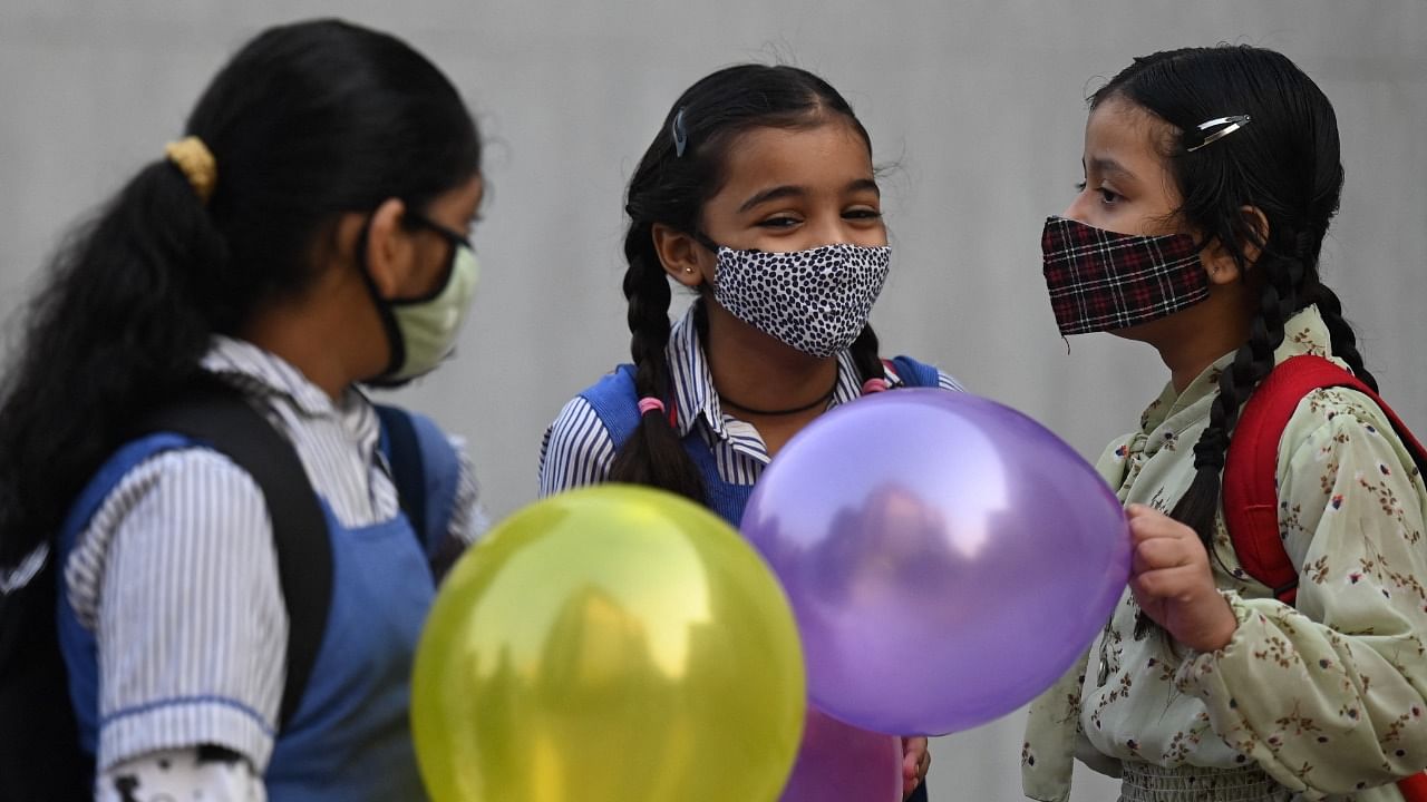 Children hold balloons as they enter their school in New Delhi. Credit: PTI Photo