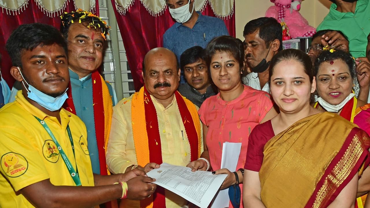 Chief Minister Basavaraj Bommai gives away caste and income certificates to Shravya at her house in Palace Guttahalli, Bengaluru, on Monday as part of Janasevaka programme. Higher Education Minister C N Ashwath Narayan is also seen. Credit: DH photo/Ranju P