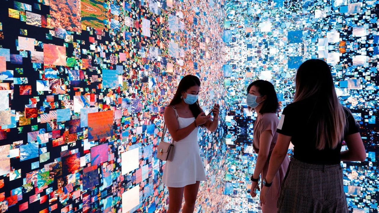 Visitors are pictured in front of an immersive art installation titled "Machine Hallucinations — Space: Metaverse" by media artist Refik Anadol, which will be converted into NFT and auctioned online at Sotheby's, at the Digital Art Fair, in Hong Kong, China. Credit: Reuters Photo