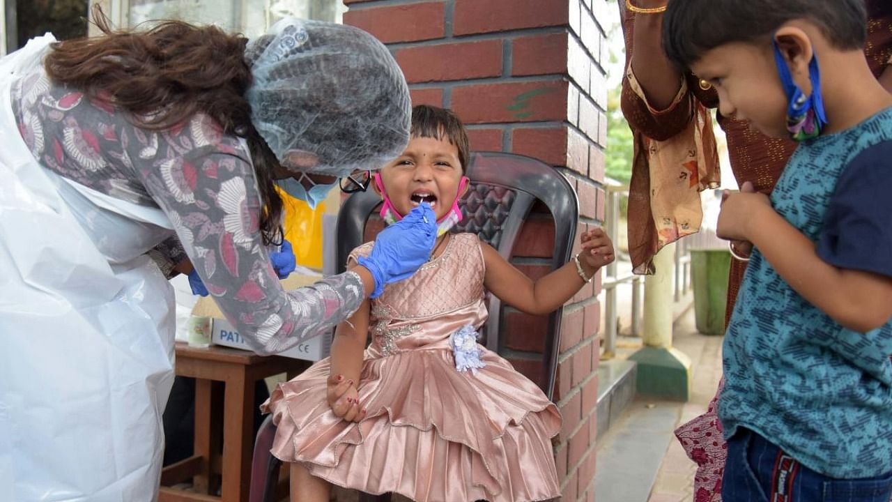 A healthcare worker takes the swab samples of a young girl for Covid-19 testing at Majestic, Bengaluru. Credit: DH File Photo/Pushkar V