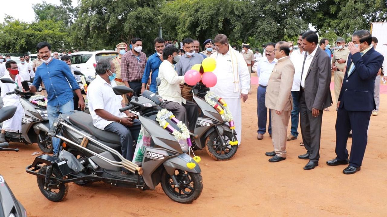Minister K Gopalaiah distributes vehicles to physically disabled persons during the Rajyotsava programme in Hassan on Monday. Deputy Commissioner R Girish is seen. Credit: DH Photo