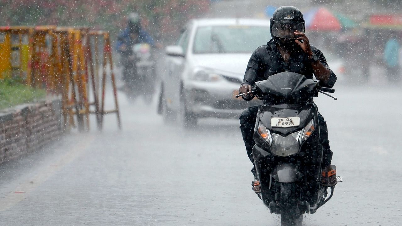 A commuter rides along a road during heavy rains in Chennai. Credit: AFP Photo