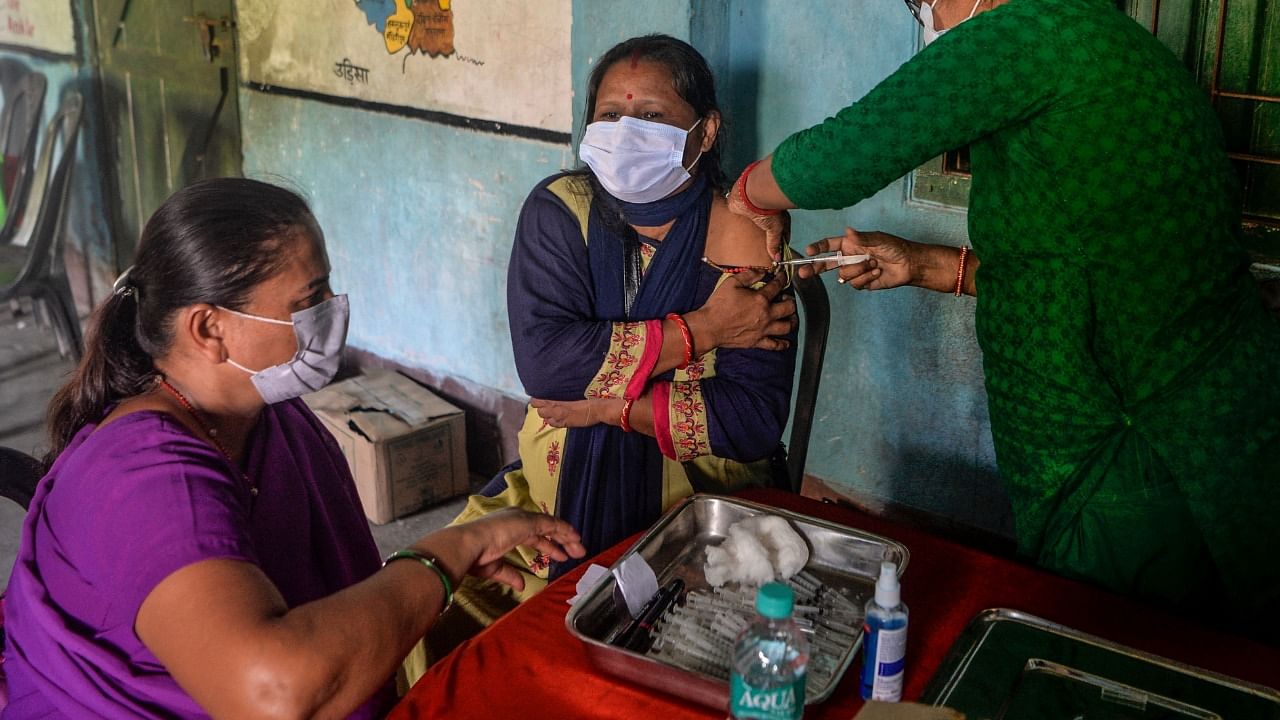 A health worker inoculates a woman with a dose of the Covishield Covid-19 vaccine at a camp in Milanmore near Siliguri. Credit: AFP File Photo