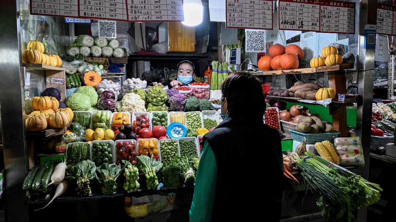 A woman browses through vegetables at a neighbourhood market in Beijing. Credit: AFP Photo