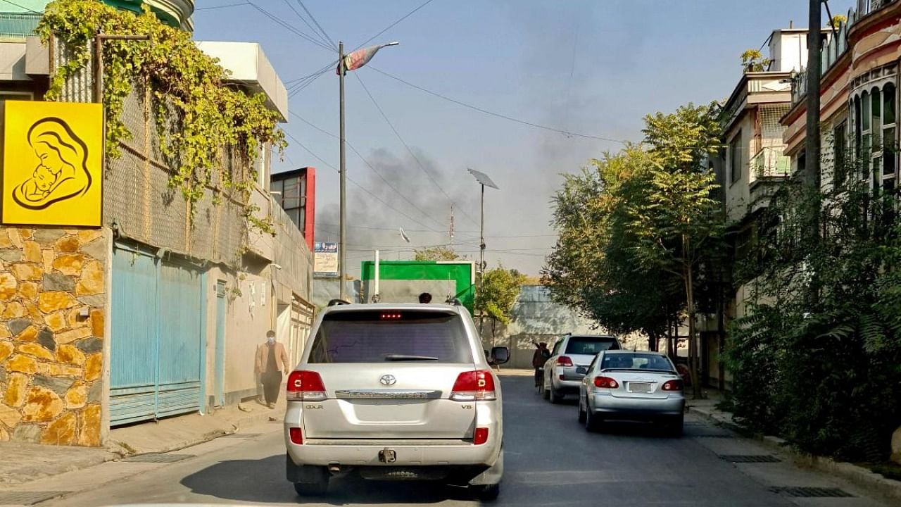 Vehicles move along a road against the backdrop of smoke rising from the site of blast in Kabul on November 2, 2021, after Afghanistan's capital was hit by two blasts near a military hospital, Taliban officials said, with a witness also reporting gunfire. Credit: AFP Photo