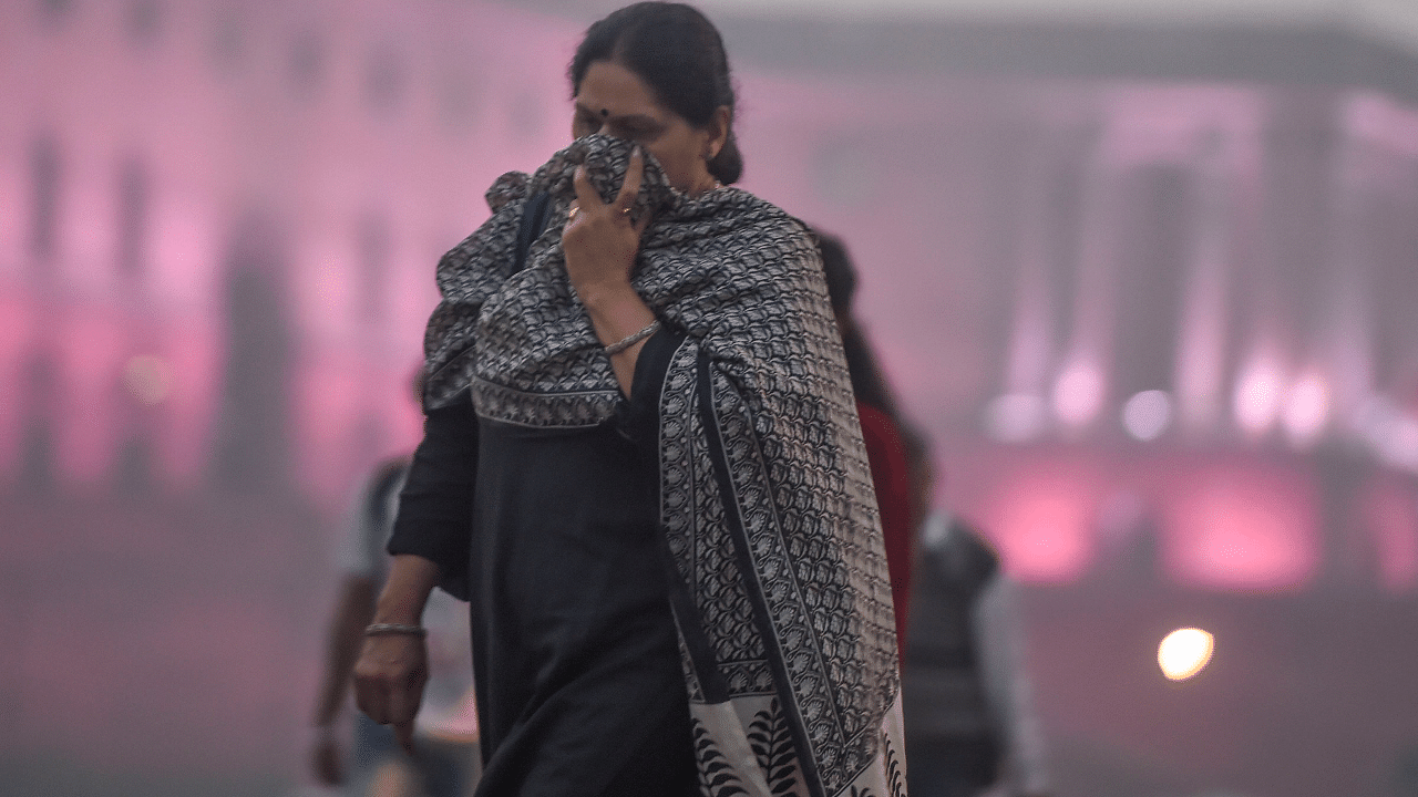 Pedestrian cover their face amid heavy smog as the air quality further dips to 'severe' category, at Vijay Chowk in New Delhi. Credit: PTI Photo