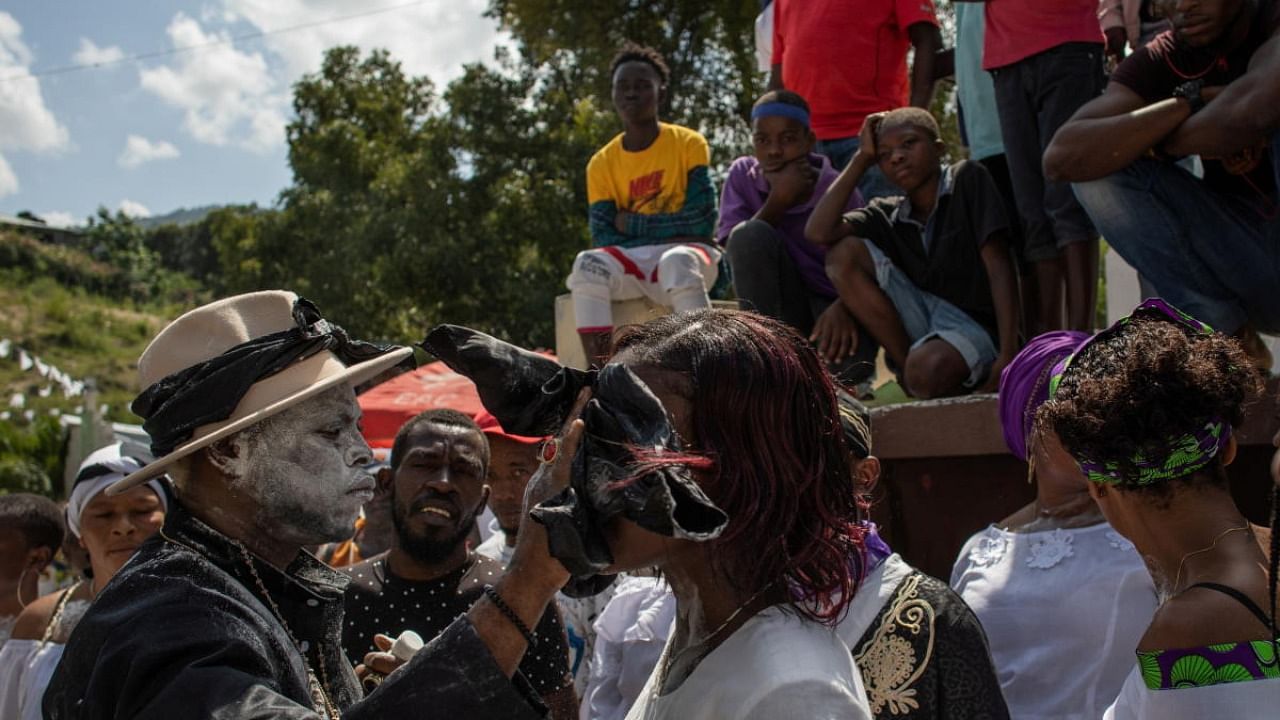Valcin Antoine "Toutout", an Ougan or Voodoo priest, wipes the faces of Voodoo followers, called Pitit Fey, as they attend a ceremony during the Day of the Dead celebrations at the Meyotte cemetery in Kay Gouye, in Port-au-Prince, Haiti. Credit: Reuters photo