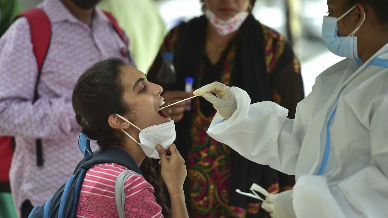 A health worker collects samples of passengers for Covid-19 test at city railway station during Covid-induced lockdown in Bengaluru. Credit: PTI File Photo