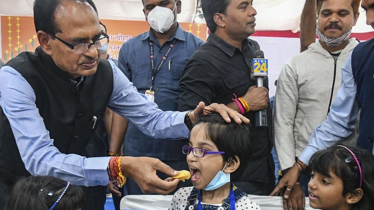 Madhya Pradesh Chief Minister Shivraj Singh Chouhan offers food to orphan children, who lost their parents during the onslaught of the Covid-19 pandemic. Credit: PTI Photo