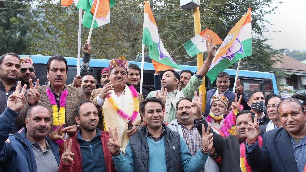MLA Sunder Singh Thakur and other Congress workers show victory sign as the party is leading during the counting of votes of Mandi parliamentary constituency by-elections, in Kullu, Tuesday. Credit: PTI Photo