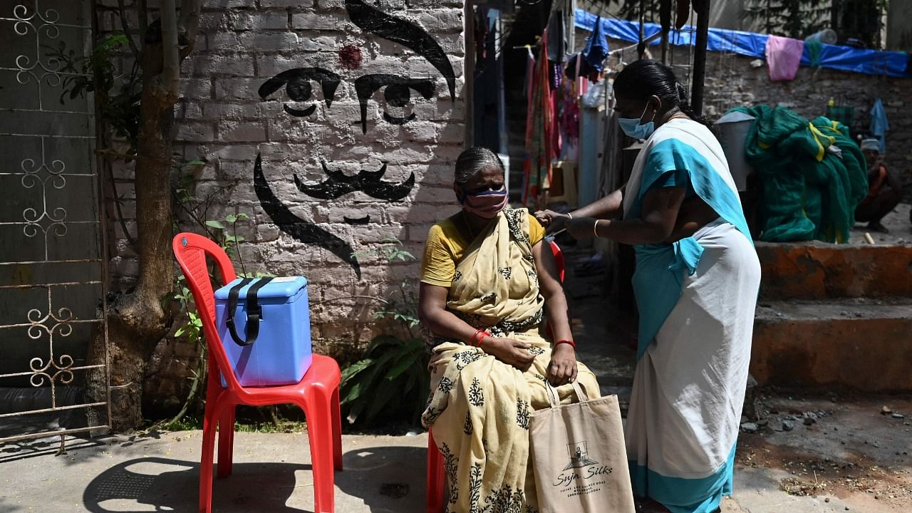  A woman reacts as a health worker inoculates her with a dose of the Covid-19 coronavirus vaccine during a door to door vaccination camp at a residential area in Chennai. Credit: AFP File Photo