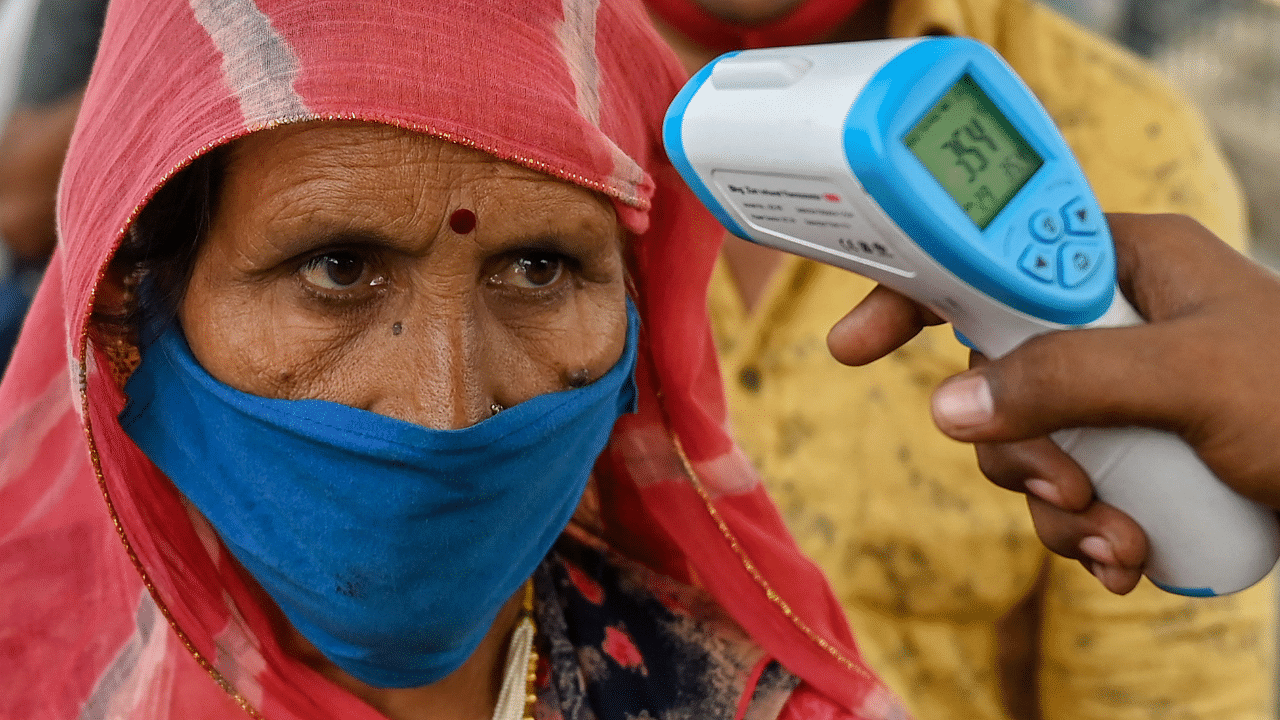 A health worker checks the temperature of a passenger during a Covid-19 coronavirus screening. Credit: AFP Photo