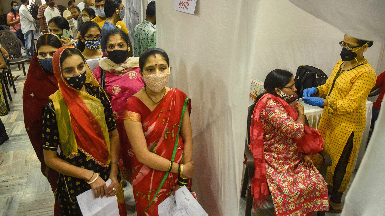 Beneficiaries wait in a queue to receive a Covid-19 vaccine dose during a free vaccination drive. Credit: PTI Photo