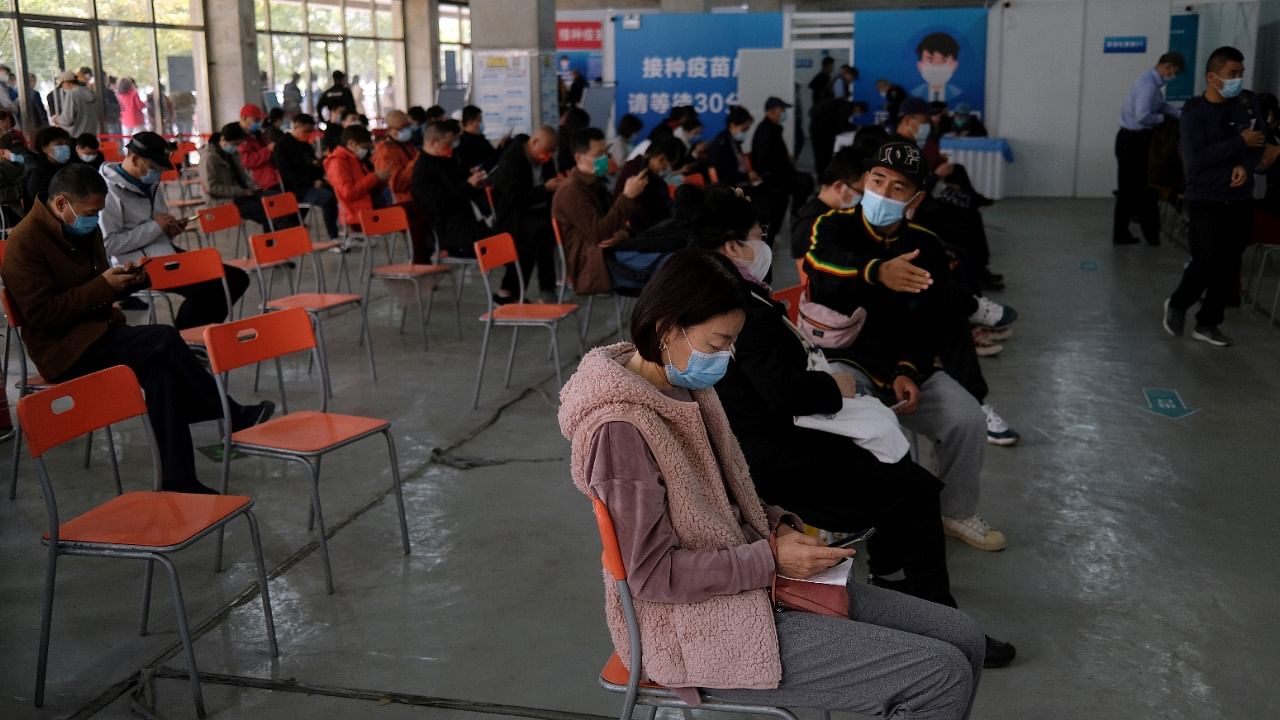People wait at an observation area after receiving booster shots of the vaccine against Covid-19 at a vaccination site in Beijing, China. Credit: Reuters File Photo
