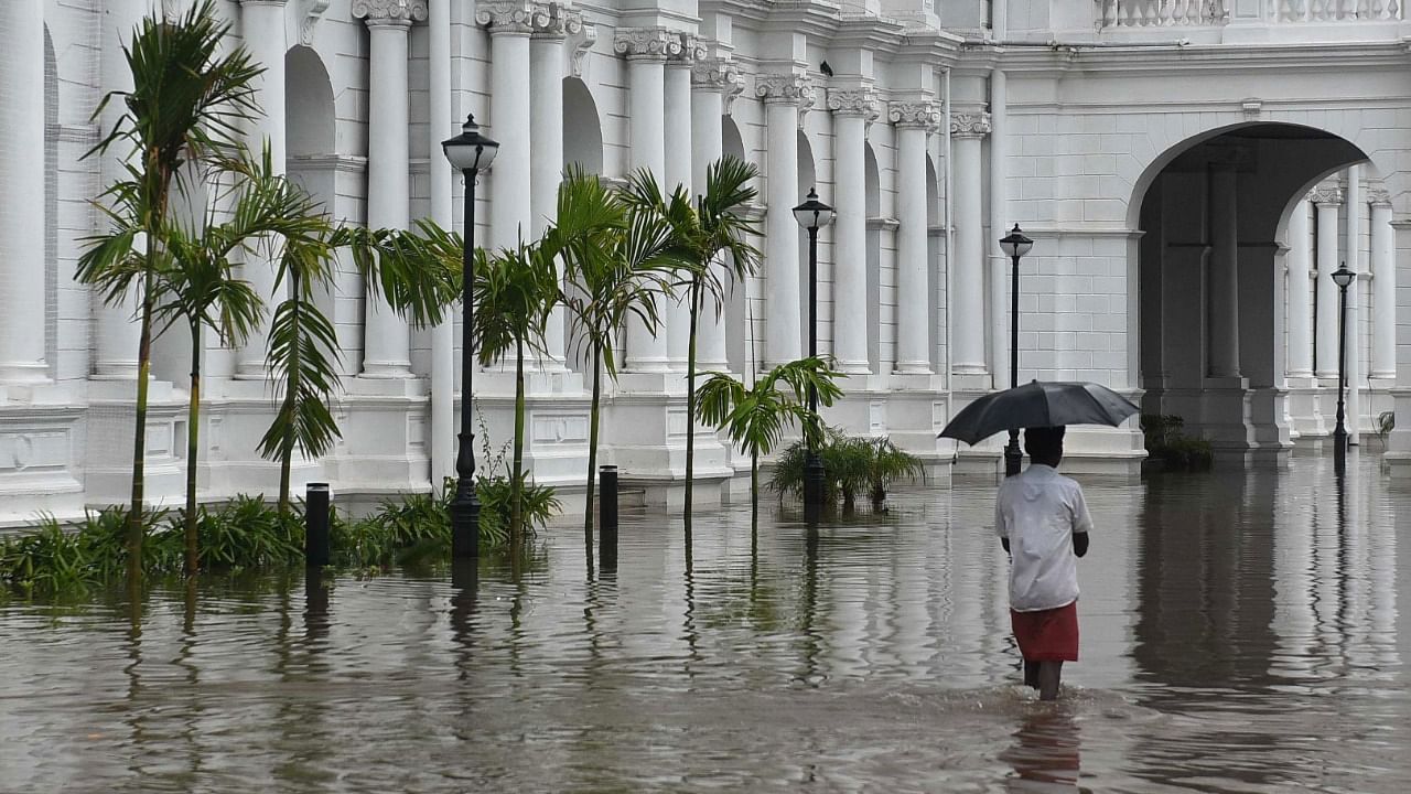A man walks through the flooded complex of Ripon Building during a rain shower in Chennai on November 7, 2021. Credit: AFP Photo