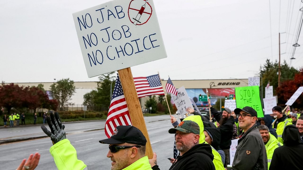 Boeing employees and others line the street with signs and American flags as they protest the company's coronavirus vaccine mandate. Credit: Reuters Photo