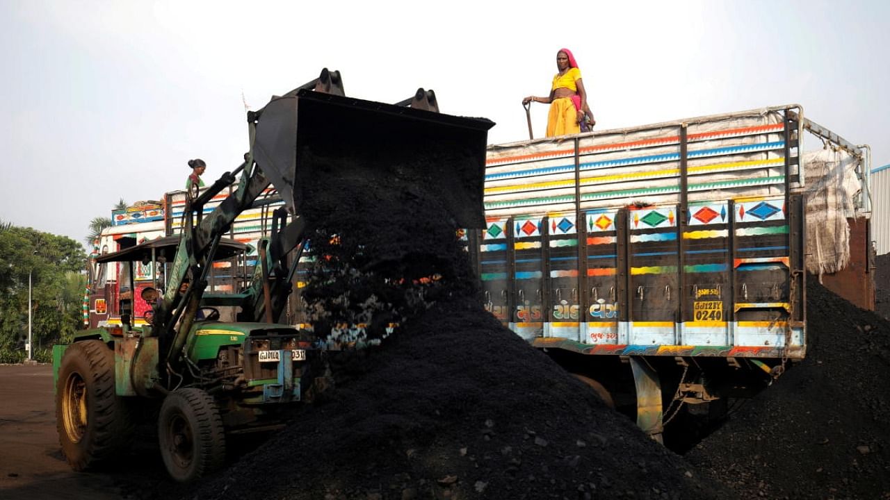 Workers unload coal from a supply truck at a yard on the outskirts of Ahmedabad. Credit: Reuters photo
