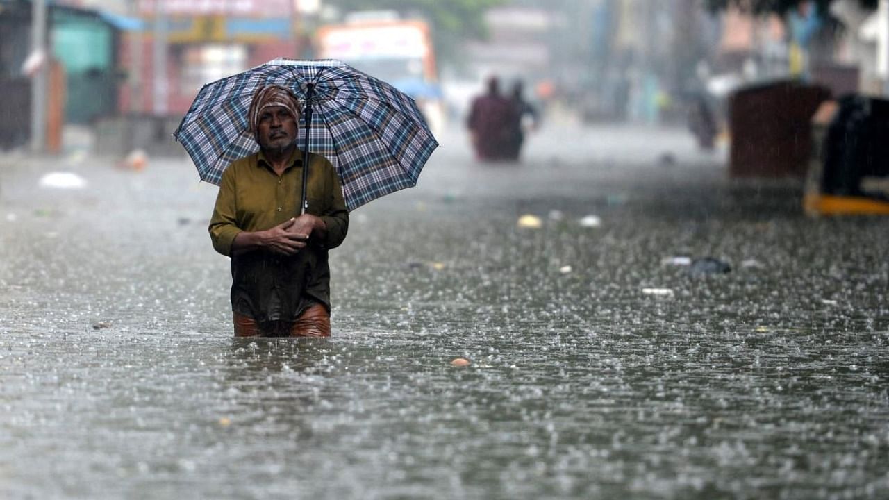 A man holds an umbrella as he wades through a flooded street after heavy monsoon rains in Chennai on November 8, 2021. Credit: AFP Photo