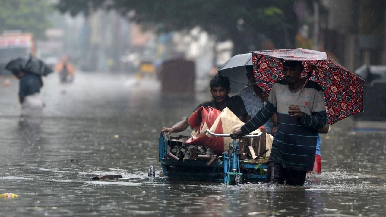 People wade through a flooded street after heavy monsoon rains in Chennai. Credit: AFP Photo