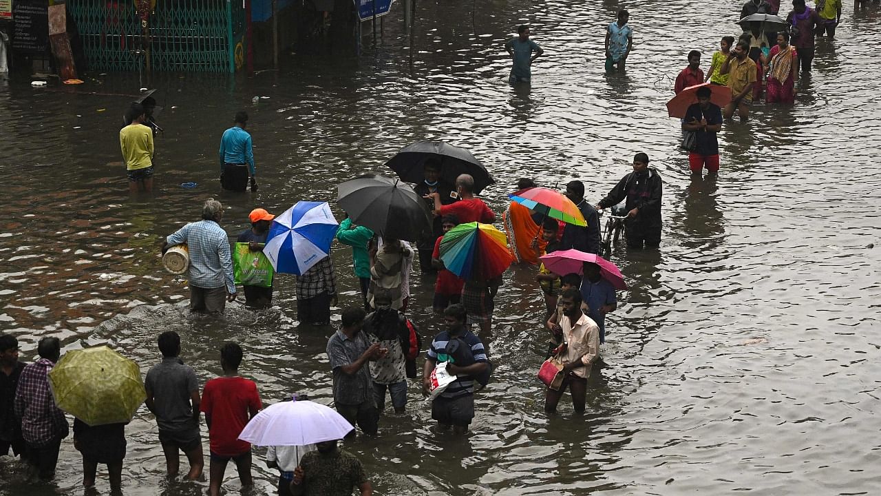 People wade through a flooded street after heavy monsoon rains in Chennai on November 8, 2021. Credit: AFP File Photo