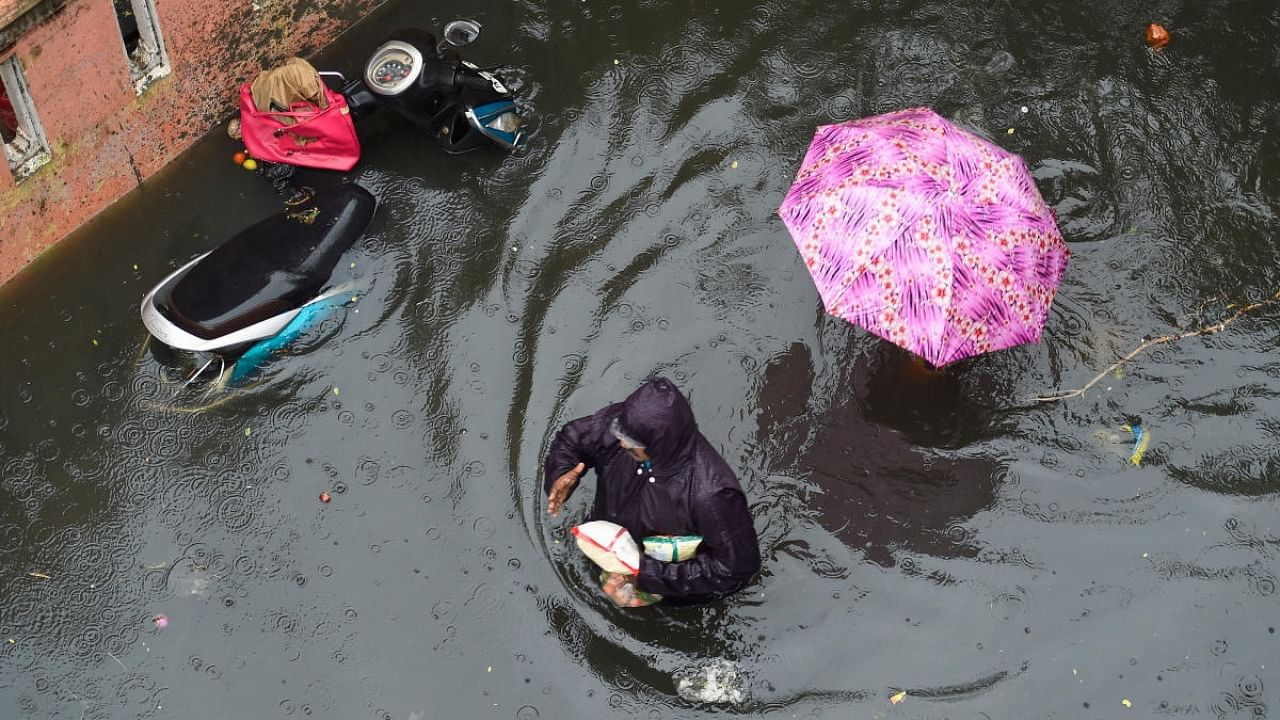 People wade through a waterlogged street following heavy rain at KM Garden in Purasaiwakkam, in Chennai. Credit: PTI Photo