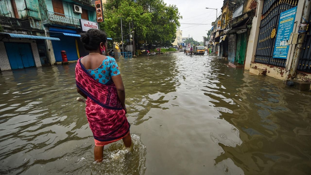 Commuters wade through a waterlogged area following heavy rain, in Chennai. Credit: PTI Photo 