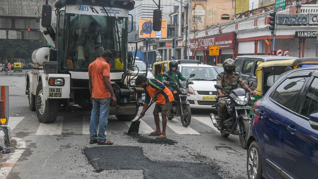BBMP workers asphalt parts of MG Road using the Python machine. Credit: DH Photo/S K Dinesh
