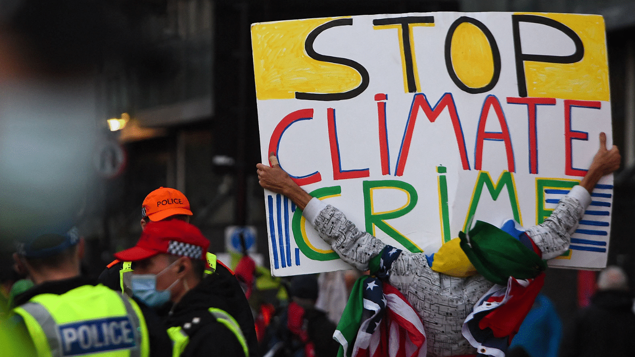 A protester holds a placard displaying a "Stop Climate Crime" slogan during a climate change demonstration outside of the COP26 Climate Change Conference in Glasgow. Credit: AFP Photo