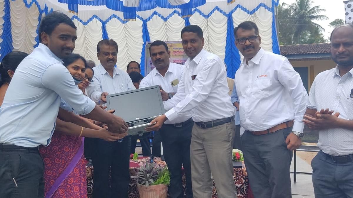 M V Sharath from Embitel Technologies India Pvt Ltd hands over a laptop to Government Higher Primary School teachers in Valnur Thyagathur.