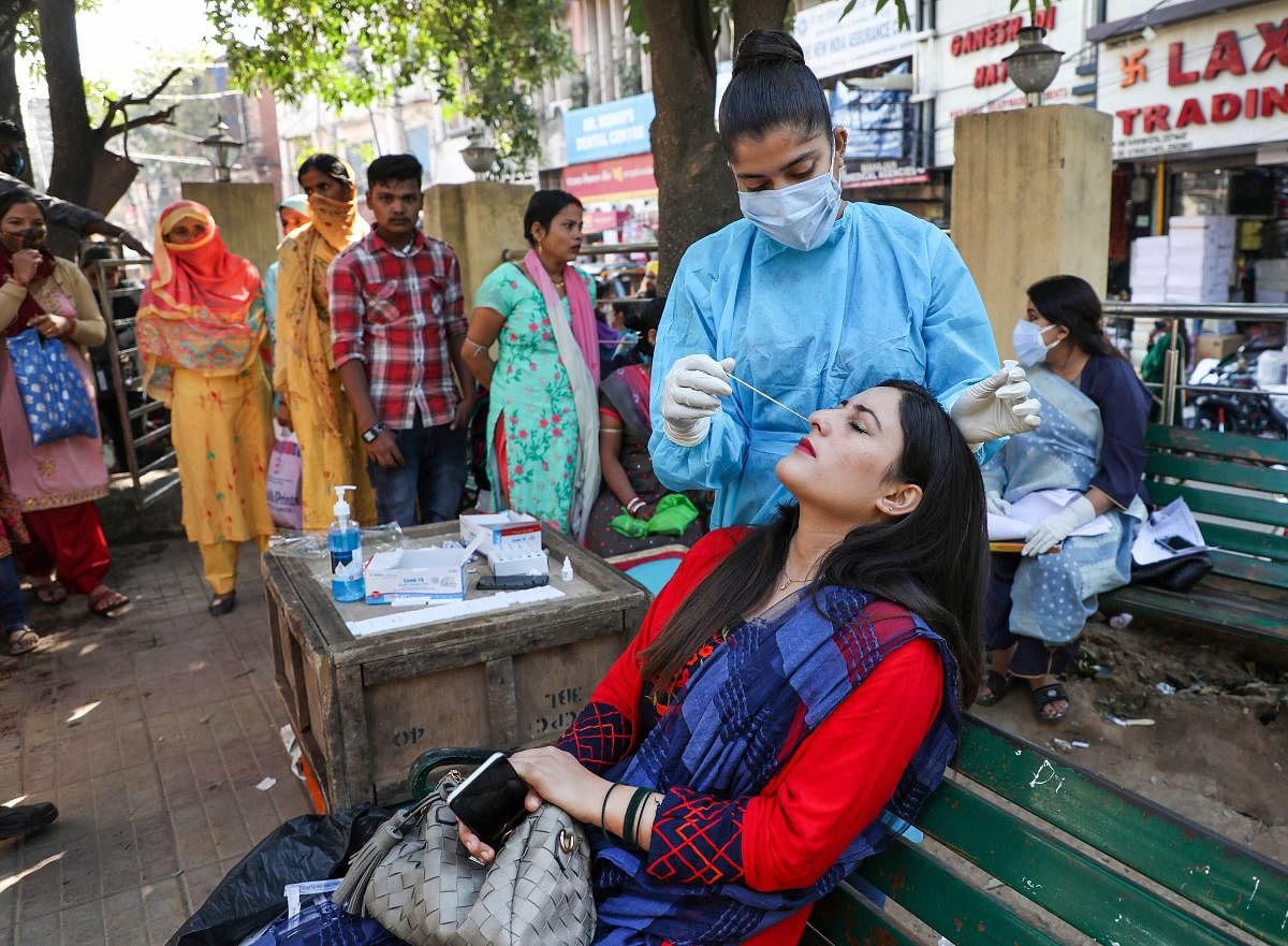 A health worker collects swab samples of a woman in Jammu. Credit: PTI file photo