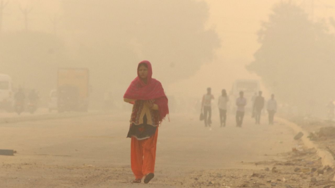 Commuters walk amid low visibility due to a thick layer of smog in Gurugram, Saturday, November 13, 2021. Credit: PTI Photo