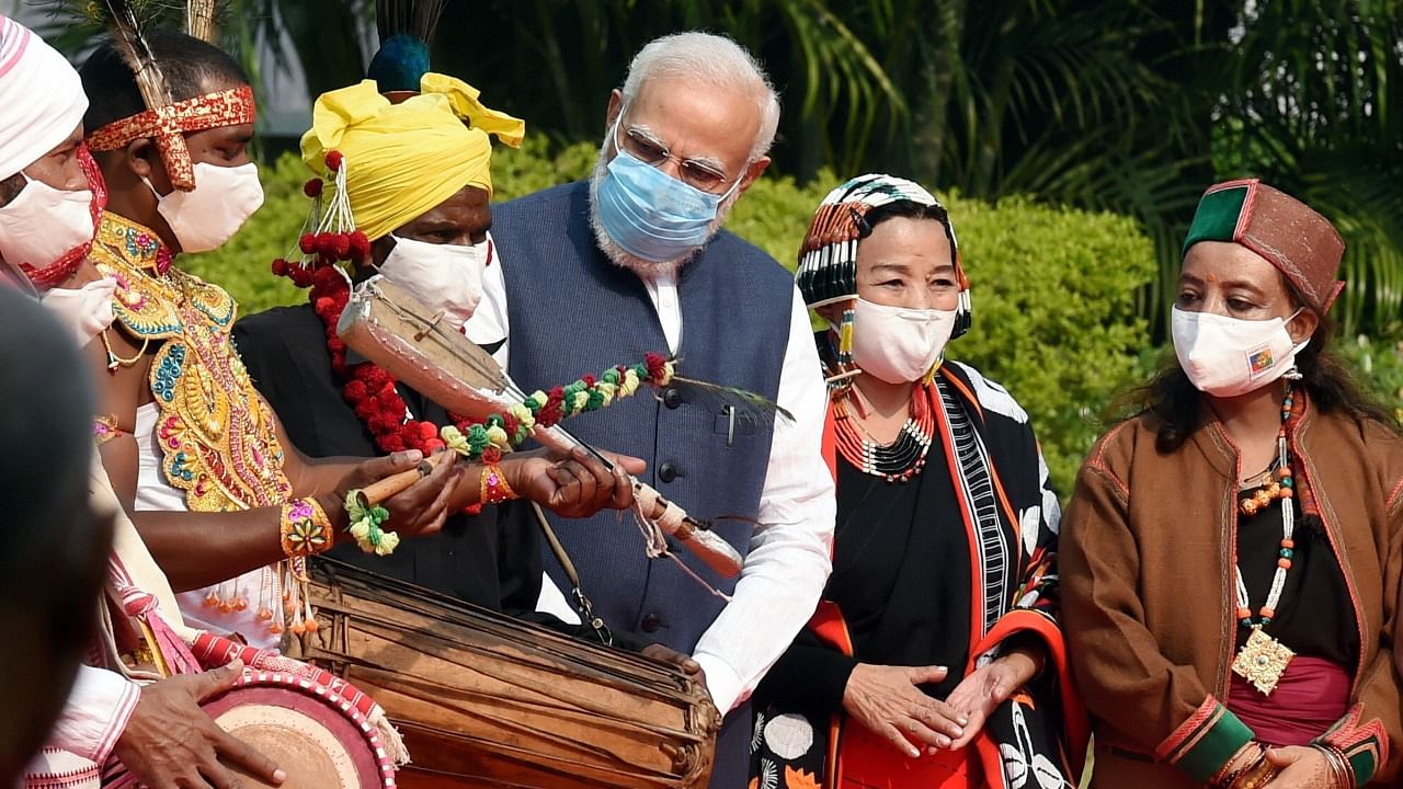 Prime Minister Narendra Modi interacts with drummers during the tribute paying ceremony of tribal leader Birsa Munda on his birth anniversary at Parliament, in New Delhi. Credit: PTI Photo