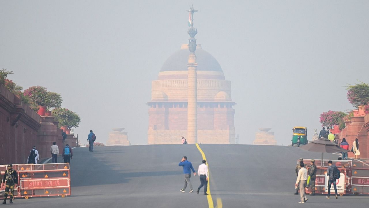 People walk near the presidential palace amid heavy smoggy conditions in New Delhi on November 15, 2021. Credit: AFP File Photo