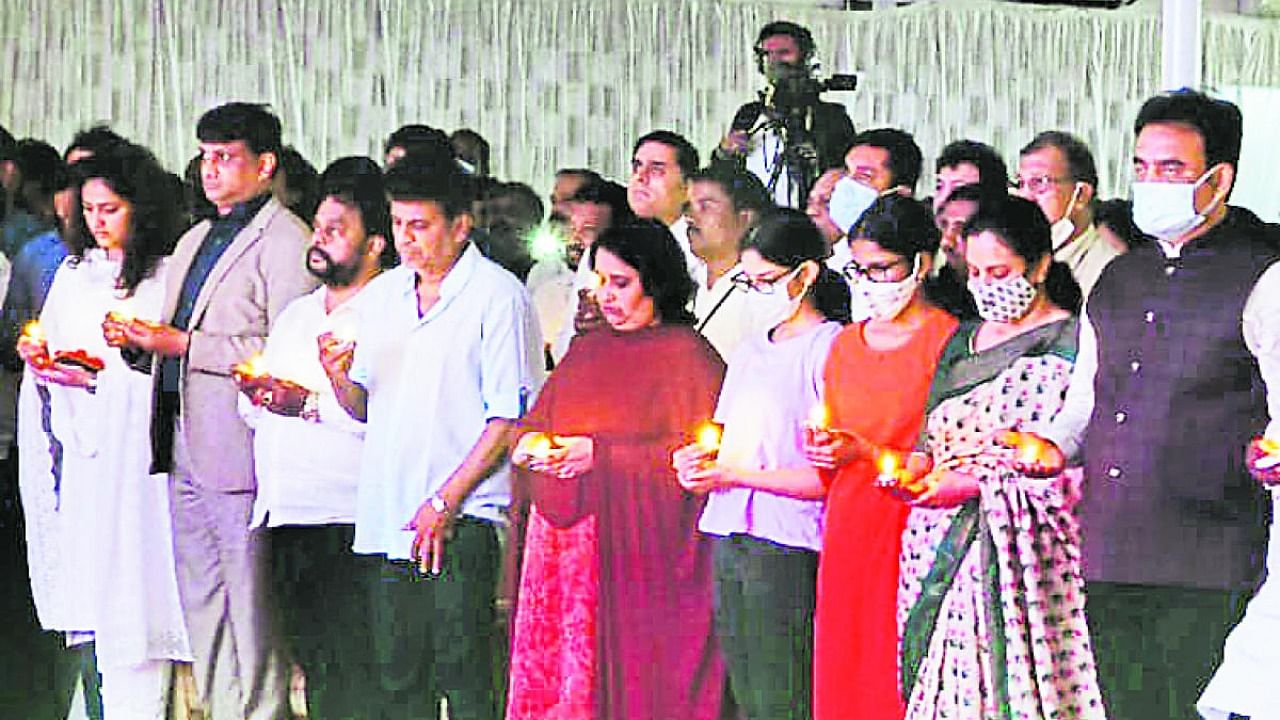Actor Shivarajkumar and others hold lamps during ‘Puneeth Namana’ programme. Credit: DH Photo