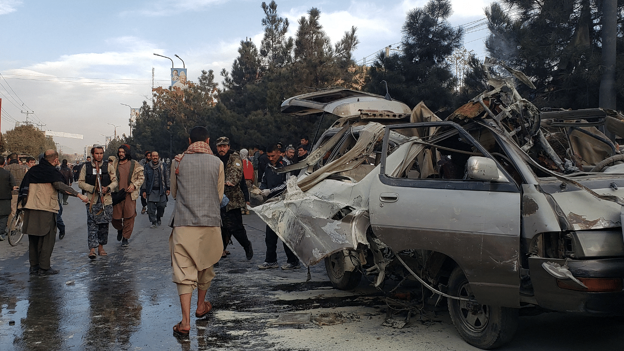 Residents gather next to a damaged minibus after a bomb blast where two people were killed and five wounded in Kabul. Credit: AFP Photo