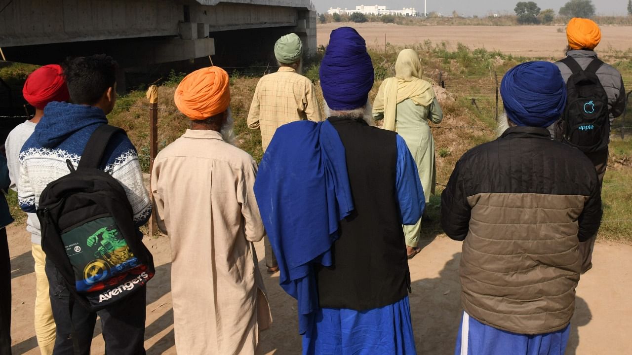 Sikh devotees offers prayers as they look towards the Gurdwara Kartarpur Sahib, which is situated in Pakistan, at the Sri Kartarpur Sahib corridor some 25 Km from Batala. Credit: AFP Photo