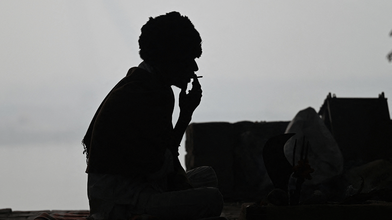 A man is silhouetted as he smokes on the banks of Yamuna river. Credit: AFP Photo