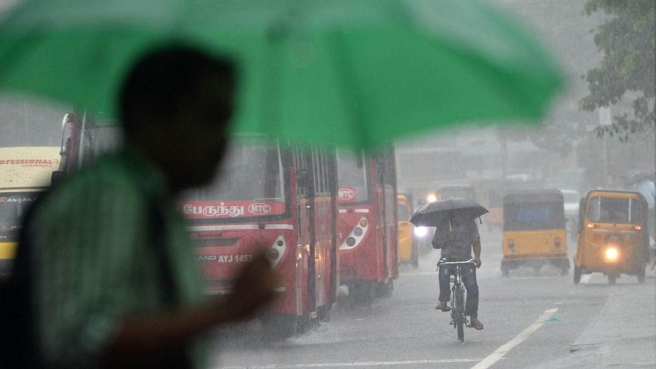 Commuters make their way through a street during a heavy rain shower in Chennai. Credit: AFP Photo