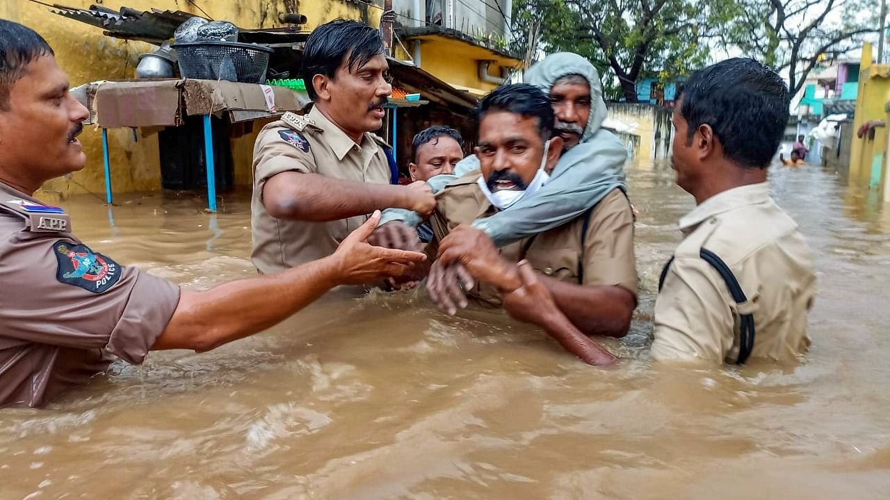 A policeman carries an old man on his back to evacuate him from a flooded area at Rajampet in Kadapa district. Credit: PTI Photo