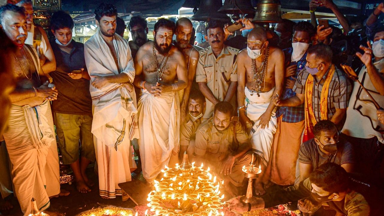 Devaswom employees and police officials light the 'Karthika lamp' in the presence of Sabarimala Melshanthi N Parameswaran Namboothiri (C), at Sabarimala temple in Pathanamthitta. Credit: PTI File Photo
