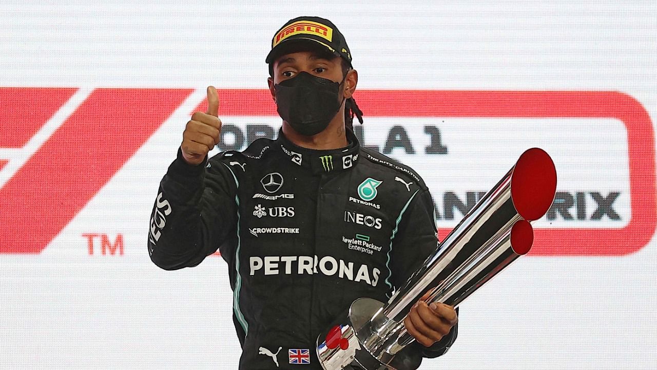 Lewis Hamilton celebrates with his 1st-place trophy on the podium following the Qatari Formula One Grand Prix at the Losail International Circuit. Credit: AFP File Photo
