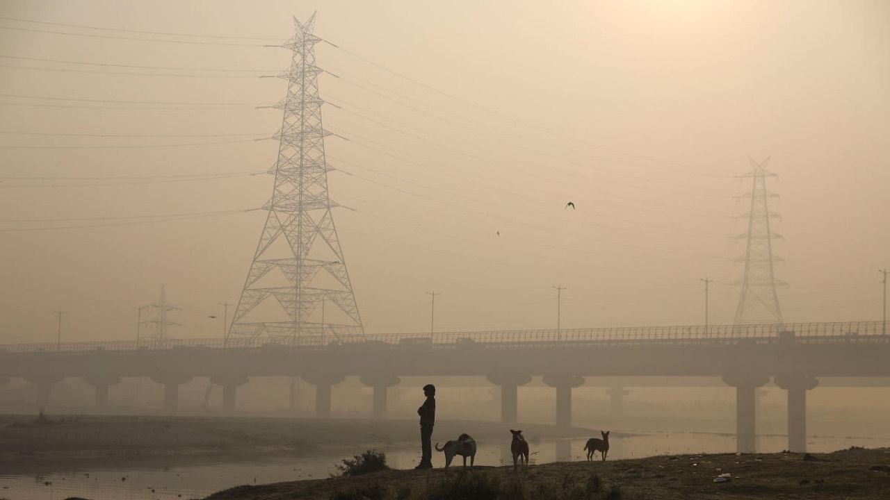 A man stands on the banks of the Yamuna river on a smoggy morning in New Delhi. Credit: Reuters Photo