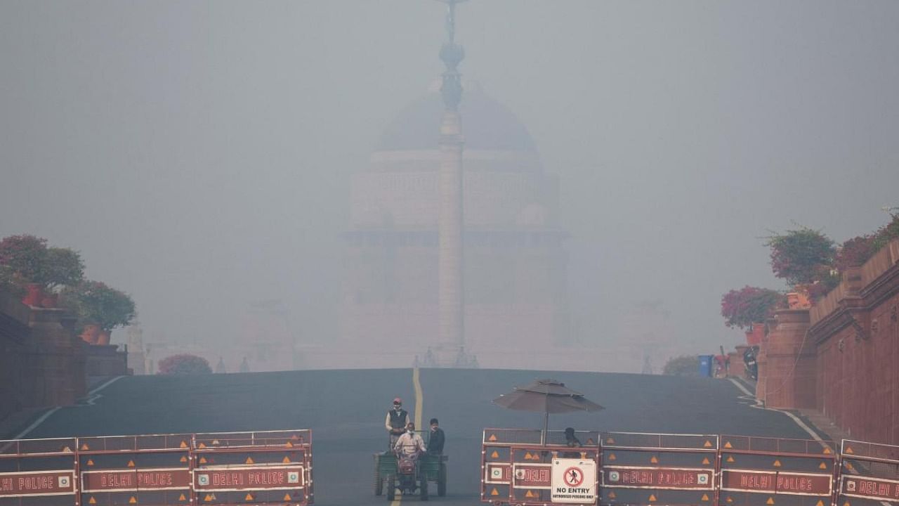 Men ride on a tractor near the Presidential Palace amid heavy smoggy conditions in New Delhi. Credit: AFP Photo